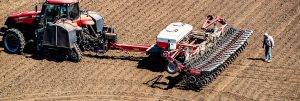 Farmer inspecting tillers on back of tractor in field