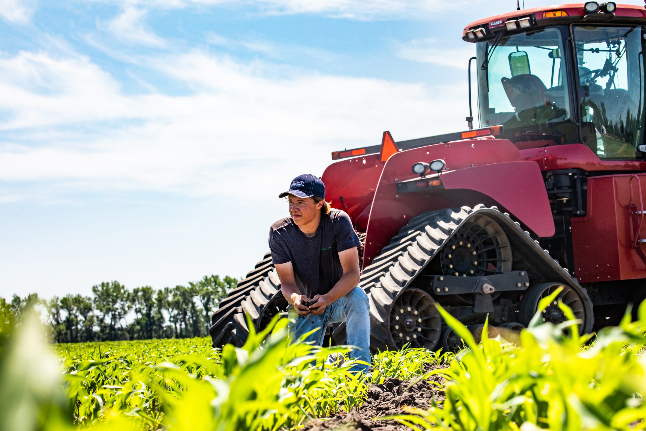 Man crouching beside a tractor in a field