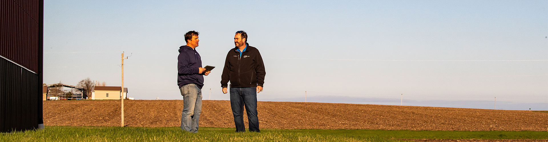 Two men talking beside an open field
